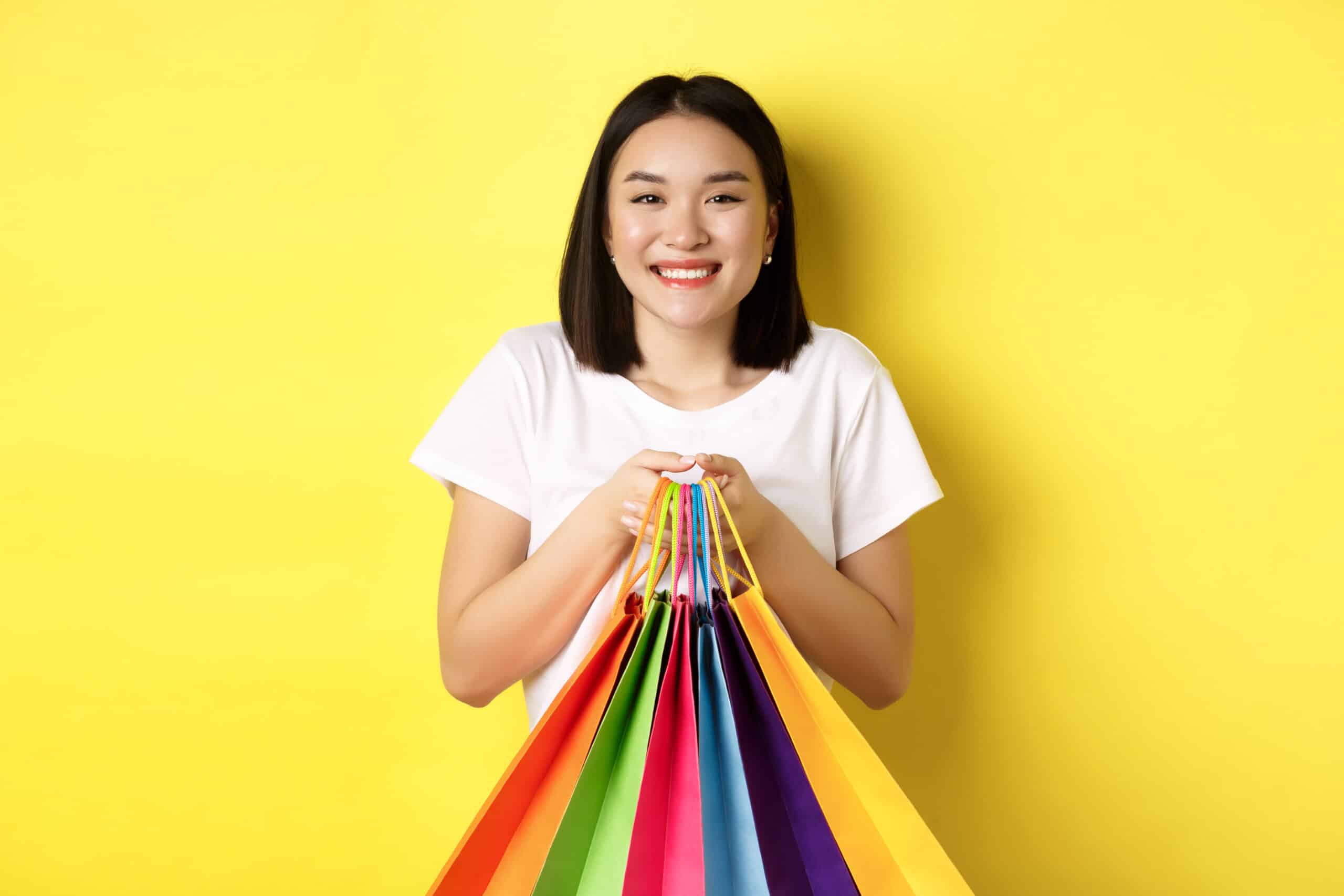 Podium magasin points clés femme tendant sacs course fond jaune