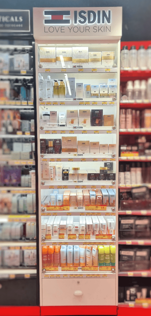  PLV ISDIN en France, conçu par Mayence. Ce meuble moderne et épuré expose une variété de produits de soins de la peau dans une pharmacie, reflétant les couleurs et l'identité de la marque ISDIN